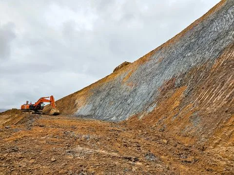 Excavator machine profiling slopes in open pit mine Stock Photos