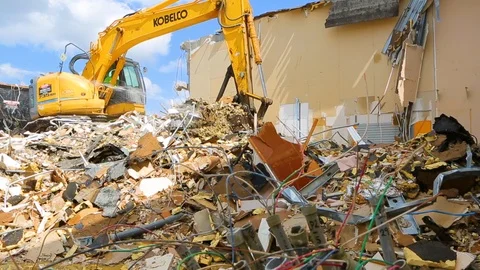 Excavator machine scooping up rubble from building demolition A Stock Footage 114926270