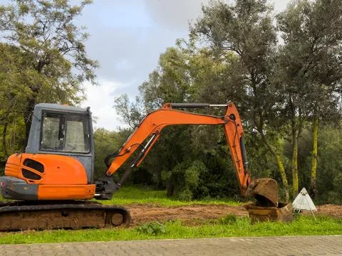 Excavator machine at work digging the ground above the hills with forest ba.. Stock Photos