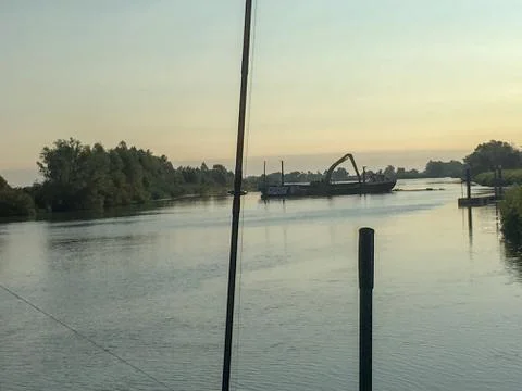 An excavator in the middle from a river Stock Photos