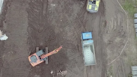 An excavator moves forward on dirt from drone view Stock Footage 169323980