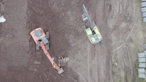 An excavator moves forward on dirt from drone view two excavators Stock Footage 169324012