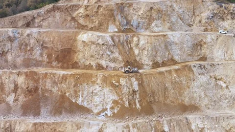 An Excavator Operating on a Terraced Mining Site, Digging Through Layers of Stock Footage 320168032