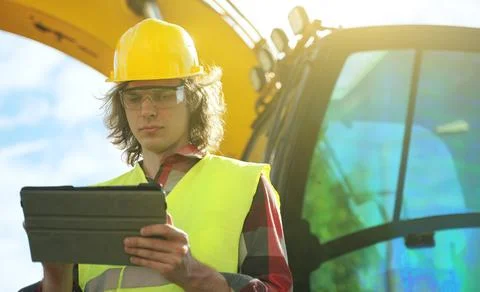 Excavator operator in hard hat using tablet pc. Foto stock