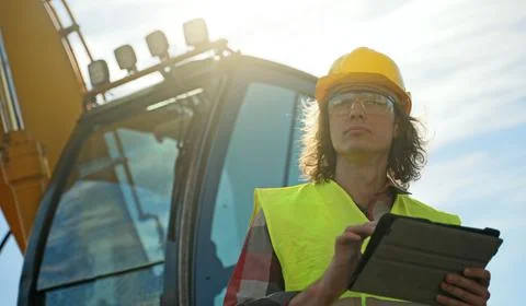 Excavator operator in hard hat using tablet pc. Foto stock