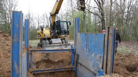 The excavator operator lowers the longitudinal shield of the trench support Stock Footage 201184705