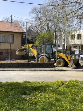 An excavator or backhoe loader dumps excavated soil into a pile at a home c.. Stock Photos