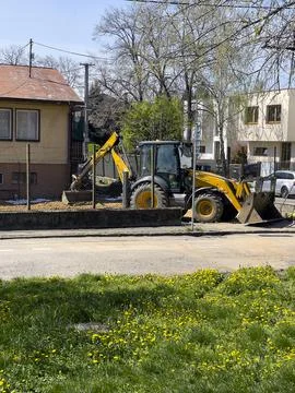 An excavator or backhoe loader dumps excavated soil into a pile at home con.. Stock Photos