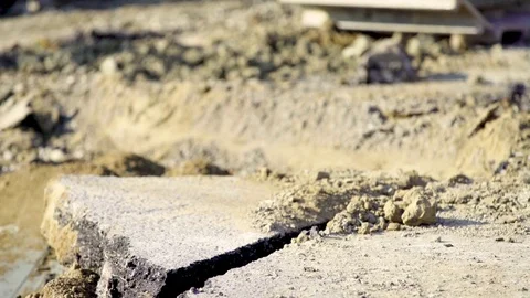 An excavator picks up a piece of broken asphalt with its bucket and then rips Stock Footage
