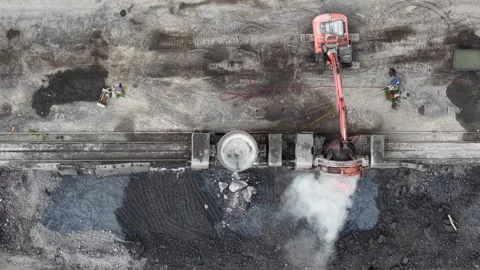 An excavator pours molten metal into a processing unit at a harsh, industrial Stock Footage 337470089