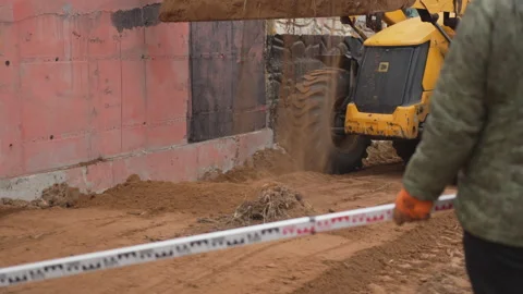 Excavator pours soil forming foundation at construction site Stock Footage 312408339