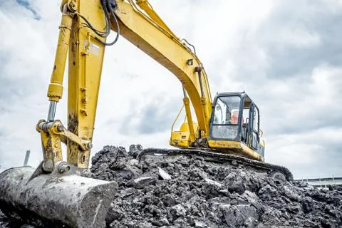 Excavator is preparing pile of ground for loading in truck on building site Stock Photos