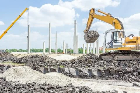 Excavator is preparing pile of ground for loading in truck on building site Stock Photos