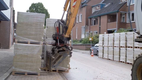 Excavator Putting Down Filled Pallets At A Village Stock Footage 129398791