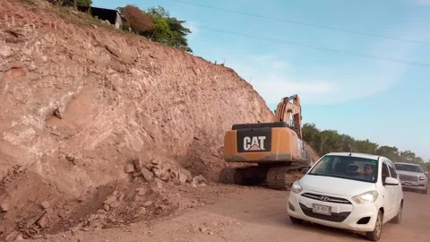 Excavator Removing Earth From Roadside Slope During Road Construction With Car Vídeos de archivo 345888559