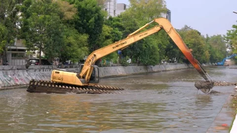 Excavator in a river digging cumulative dirt that shallowing the river Stock Footage 318751127