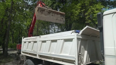 Excavator scoop loading excavated ground  in trailer of tipper truck. Stock Footage 76693475