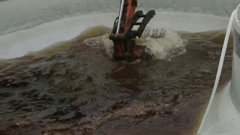 Excavator scooping water from old pool   close Stockbeeldmateriaal 71563897