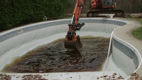 Excavator scooping water from old pool   long   no sound Stockbeeldmateriaal 71564066