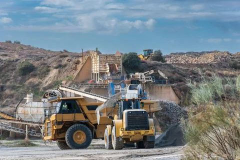 Excavator shovel loading a large dump truck in a sand and gravel quarry. Stock Photos