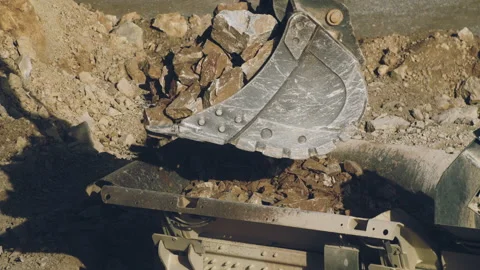 Excavator shovel unloading stone pieces in rock crusher machine, quarry open pit Video stock 294103255