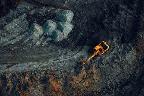 Excavator at work on a dark background. Top view from a drone Stock Photos