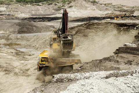 Excavator at work in the open-pit mine - industrial machinery digger coal lig Stock Photos
