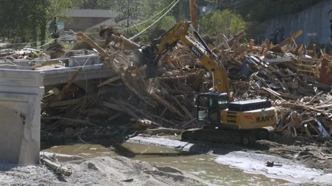 Excavator working to clear debris from river left behind after Hurricane Helene Stock Footage 287996611