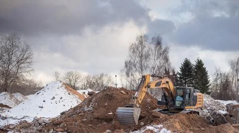 Excavator working at construction site. Backhoe digs ground Stock Photos