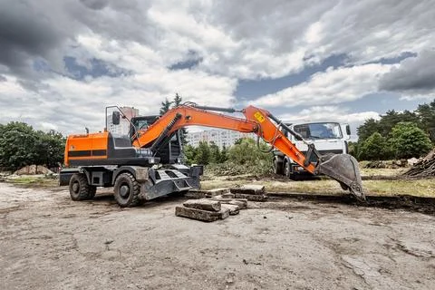 An excavator is working at a construction site, moving soil and rocks, and a  Stock Photos