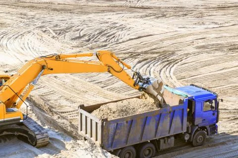 Excavator working on sand quarry. Loading the dump truck with sand. Stock Photos