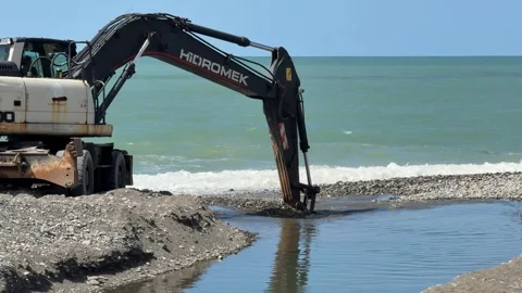 Excavator working by seaside during daylight with clear sky, showing indust.. Stock Footage 338324611