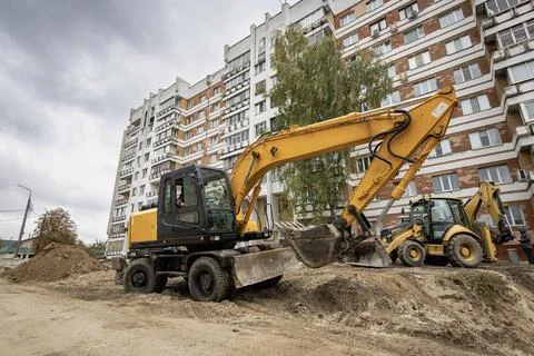 Excavators are working to move soil at a construction site next to residentia 库存照片