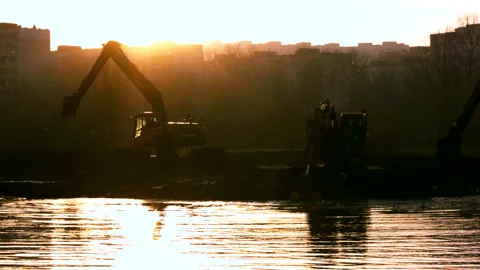 Excavators cleans and deepens the river bed at sunset. Stock Footage 98687732