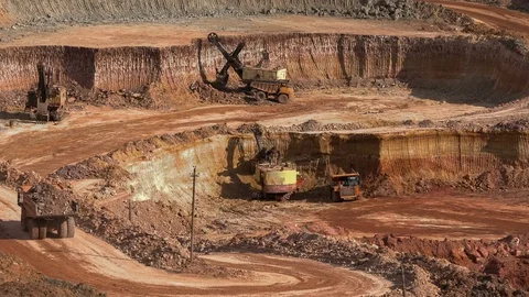 Excavators load ore into dump-trucks. This area has been mined for buaxite Stock Footage 75042381