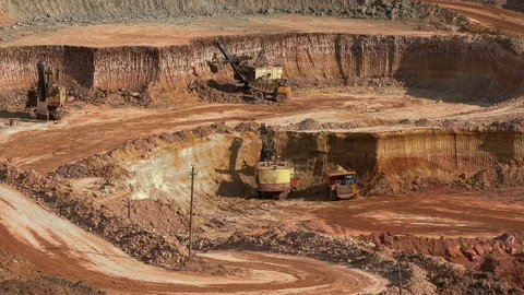 Excavators load ore into dump-trucks. This area has been mined for buaxite Stock Footage 75042750
