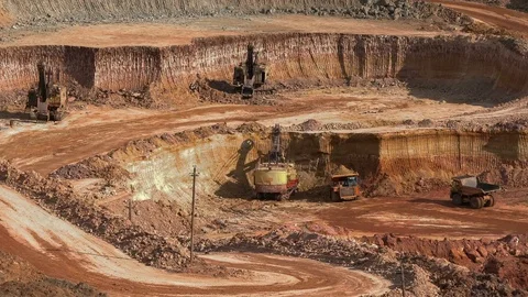 Excavators load ore into dump-trucks. This area has been mined for buaxite Stock Footage 75043283