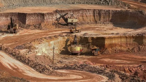 Excavators load ore into dump-trucks. This area has been mined for buaxite Stock Footage