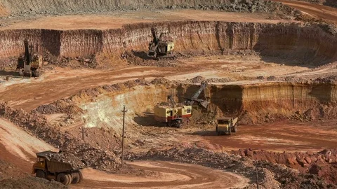 Excavators load ore into dump-trucks. This area has been mined for buaxite Stock Footage 75294528
