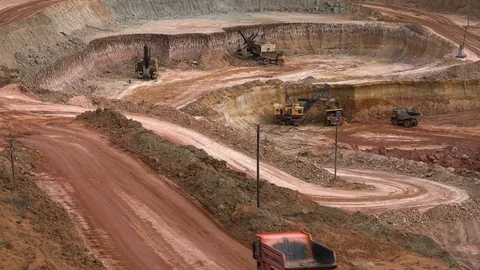 Excavators load ore into dump-trucks. This area has been mined for buaxite 库存影片 75297343