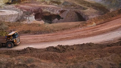 Excavators load ore into dump-trucks. This area has been mined for buaxite Stock Footage 75379176