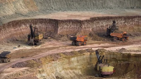 Excavators load ore into dump-trucks. This area has been mined for buaxite Stock Footage 75389191
