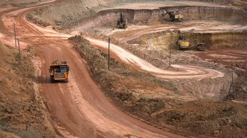 Excavators load ore into dump-trucks. This area has been mined for buaxite Stock Footage 75461762