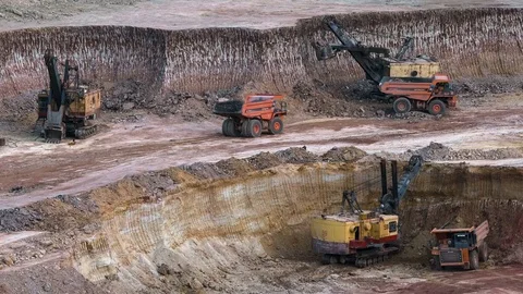 Excavators load ore into dump-trucks. This area has been mined for buaxite Stock Footage 75462006