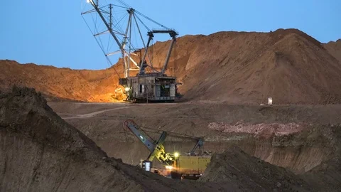 Excavators load ore into dump-trucks. This area has been mined for buaxite Stock Footage 75580004