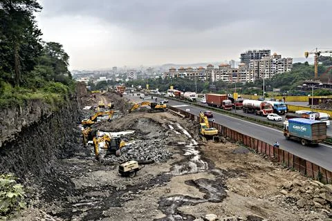 Excavators of various companies digging simultaneously for road widening work Stock Photos