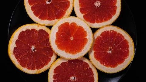 Excellent concentric top view of fresh red grape-fruit slices on black dish Stock Footage 76964687