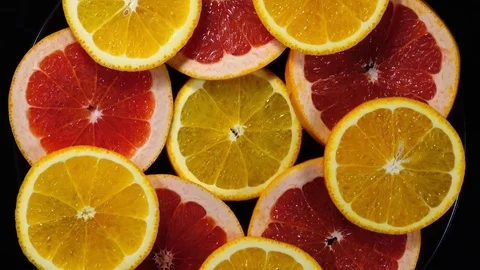 Excellent concentric top view of orange and red grape-fruit slices on black dish Stock Footage 73870800