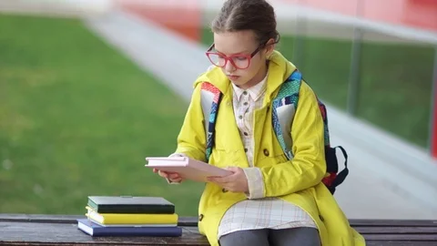 An excellent student in a yellow jacket and glasses sits on a bench near the Stock Footage 106112355