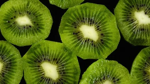 Excellent top view of fresh sliced kiwi-fruit on dark dish, concentric rotating Stock Footage 74694091
